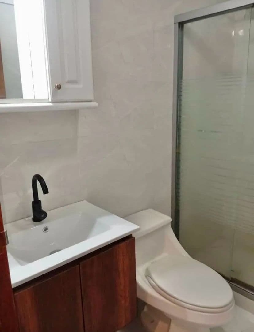 Baño con ducha de vidrio y mueble de madera